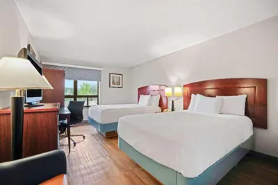a hotel room with two beds and a desk at Days Inn by Wyndham Utica in Utica