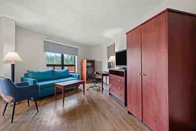 a living room with a blue couch and a desk at Days Inn by Wyndham Utica in Utica