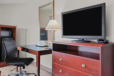 a room with a desk with a television and a chair at Days Inn by Wyndham Utica in Utica