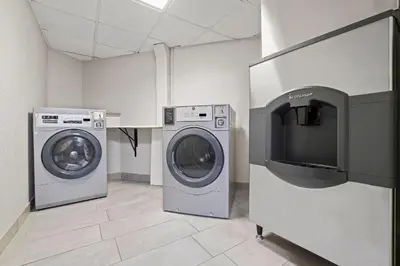 a laundry room with two washing machines and a tv at Days Inn by Wyndham Utica in Utica