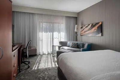 a hotel room with a bed and a couch and a desk at Courtyard by Marriott Mahwah in Mahwah