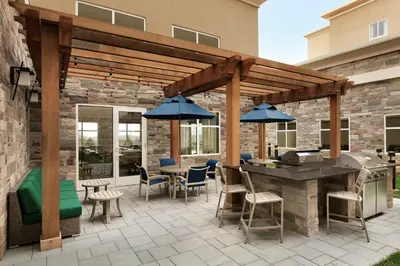 a patio with an outdoor kitchen with a wooden pergola at Homewood Suites By Hilton Hartford Manchester in Manchester