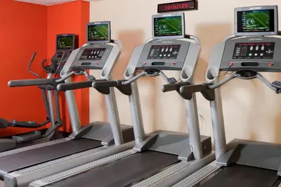 a gym with three treadying machines and cell phones at Courtyard By Marriott Jersey City Newport in Jersey City