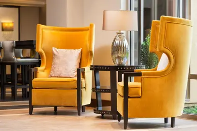 two orange chairs and a table with a lamp at Sheraton Hartford South in Rocky Hill