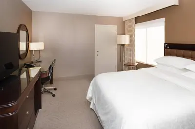 a hotel room with a bed and a desk and a television at Sheraton Hartford South in Rocky Hill