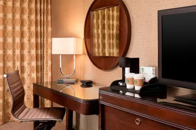 a hotel room with a desk with a television and a mirror at Sheraton Hartford South in Rocky Hill