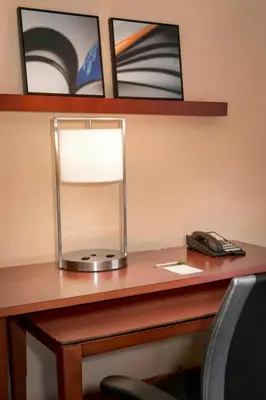 a desk with a lamp and a phone on it at Courtyard By Marriott Hartford Windsor Airport in Windsor