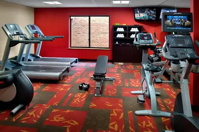 a gym with cardio equipment in a room with red walls at Courtyard By Marriott Hartford Windsor Airport in Windsor