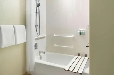 a bathroom with a tub and a shower with a bench at Courtyard By Marriott Hartford Windsor Airport in Windsor