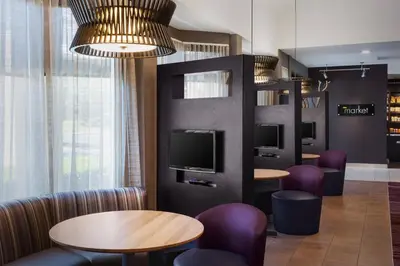 a waiting room with tables and chairs and a tv at Courtyard by Marriott Fishkill in Fishkill