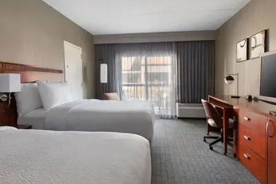 a hotel room with two beds and a desk and a television at Courtyard by Marriott Tarrytown Westchester County in Tarrytown