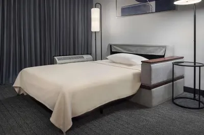 a bedroom with a large white bed and a lamp at Courtyard by Marriott Norwalk in Norwalk