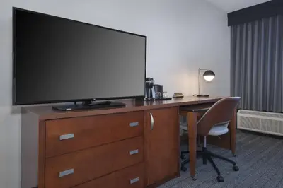 a desk with a television on top of a dresser at Courtyard by Marriott Norwalk in Norwalk