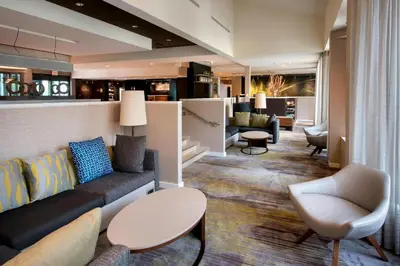 a living room with a couch and chairs and a bar at Courtyard by Marriott Norwalk in Norwalk