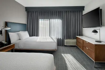 a hotel room with two beds and a flat screen tv at Courtyard by Marriott Rye in Rye
