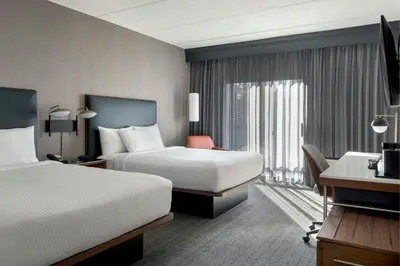 a hotel room with two beds and a desk at Courtyard by Marriott Rye in Rye