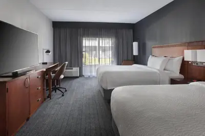 a hotel room with two beds and a flat screen tv at Courtyard by Marriott Poughkeepsie in Poughkeepsie