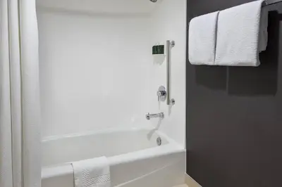 a white bathroom with a bath tub and towels at Courtyard by Marriott Poughkeepsie in Poughkeepsie