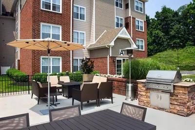 a patio with a table and an umbrella and a grill at Residence Inn Poughkeepsie in Poughkeepsie