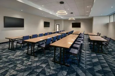 a conference room with wooden tables and blue chairs at Courtyard by Marriott New Haven Wallingford in Wallingford