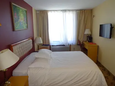 a hotel room with a large bed and a window at Flushing Hotel in Queens