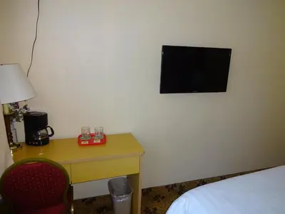 a room with a desk and a television on the wall at Flushing Hotel in Queens