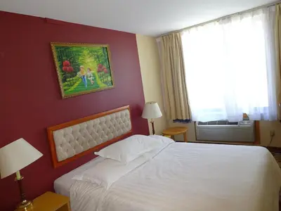 a bedroom with a white bed and a painting on the wall at Flushing Hotel in Queens