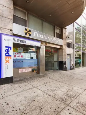 a building with a flush tying house sign on it at Flushing Hotel in Queens