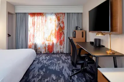 a hotel room with a bed and a desk and a bed and a room with at Fairfield Inn & Suites by Marriott Albany Airport in Albany