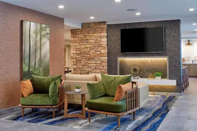 a living room with two chairs and a tv at Fairfield Inn & Suites by Marriott Albany Airport in Albany
