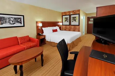 a hotel room with a bed and a red couch at Courtyard Rockaway-Mount Arlington in Mount Arlington