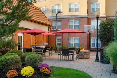 a patio with tables and chairs with red umbrellas at Residence Inn East Rutherford Meadowlands in East Rutherford