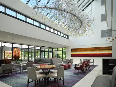 a lobby with a chandelier and tables and chairs at Hanover Marriott in Whippany