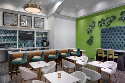 a restaurant with tables and chairs and a green wall at Courtyard by Marriott Stamford Downtown in Stamford
