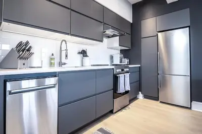 a kitchen with gray cabinets and a stainless steel refrigerator at Station Inn Pawling in Pawling