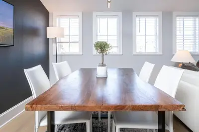 a dining room with a wooden table and white chairs at Station Inn Pawling in Pawling