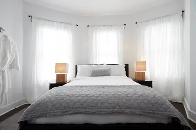 a bedroom with a bed with white curtains and two lamps at Station Inn Pawling in Pawling