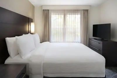 a hotel room with a white bed and a television at Residence Inn by Marriott Albany East Greenbush/Tech Valley in East Greenbush