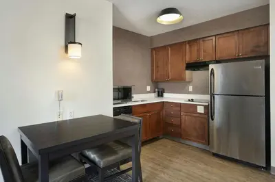 a kitchen with a table and a stainless steel refrigerator at Residence Inn by Marriott Albany East Greenbush/Tech Valley in East Greenbush