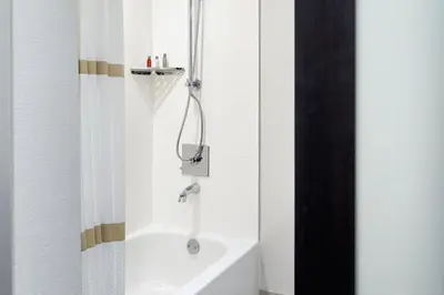 a bathroom with a shower and a white bath tub at Marriott Hartford/Windsor Airport in Windsor