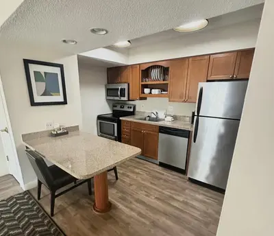 a kitchen with a table and a stainless steel refrigerator at Residence Inn by Marriott Hartford Windsor in Windsor