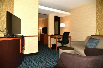 a hotel room with a couch and a desk with a television at Fairfield Inn Hartford Airport in Windsor Locks