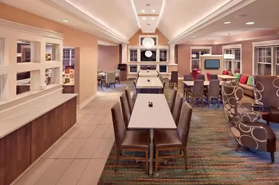 a restaurant with tables and chairs and a clock on the wall at Residence Inn Hartford Avon in Avon