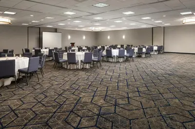 a conference room with tables and chairs and a screen at Courtyard Hartford Cromwell in Cromwell