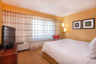 a hotel room with a bed and a flat screen tv at Courtyard Hartford Manchester in Manchester