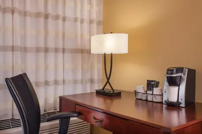 a desk with a lamp and a coffee maker on it at Courtyard Hartford Manchester in Manchester