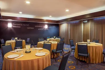 a conference room with round tables and chairs and a chalkboard at Courtyard Hartford Manchester in Manchester