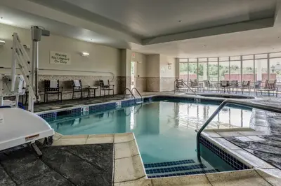 a swimming pool with blue water in a building at Courtyard Hadley Amherst in Hadley