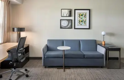 a living room with a blue couch and a table at Residence Inn Hartford Manchester in Manchester
