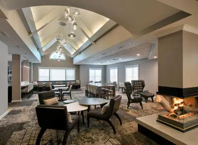 a lobby with tables and chairs and a fireplace at Residence Inn Hartford Manchester in Manchester